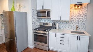 A modern kitchen with white cabinets, a stainless steel refrigerator, a built-in oven, a microwave, and a gas stove. - Remodeled Modern 1BR 1BA Apt Near Downtown 5min Pearl (San Antonio)