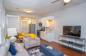 Un espacio habitable compacto con sofá, sillón, reposapiés y mueble para televisión.