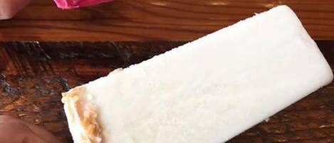 Una superficie de madera con dos helados, uno rosa y otro blanco.