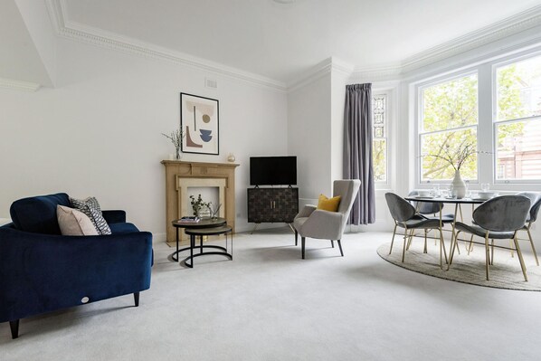 Relax in this stylish living room with a dark blue sofa, modern fireplace, and dining area.