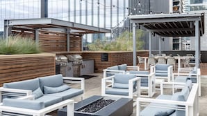 Un patio al aire libre con asientos, una parrilla y luces colgantes.