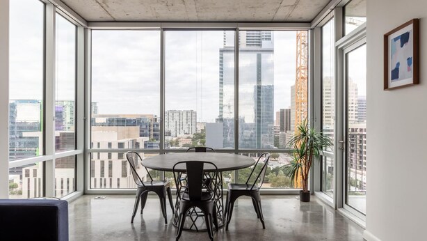 A modern room with a large window, a round table, and four chairs. - Austin Remarkable 1BD 1BA 2nd Street District Apartment (Austin)