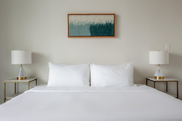 A hotel room with a large bed, two bedside tables with lamps, and a painting on the wall.