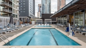 A rooftop pool with lounge chairs and umbrellas, surrounded by high-rise buildings. - Austin Remarkable 1BD 1BA 2nd Street District Apartment (Austin)