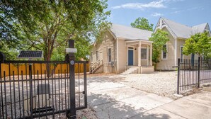 A two-story house with a front porch, a solar panel, and a gated driveway. - Incredible New 3BR 2BA Near Downtown (San Antonio)