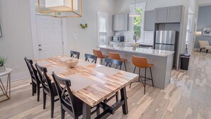 A modern kitchen with a central island, built-in appliances, and a dining area with a wooden table and chairs. - Incredible New 3BR 2BA Near Downtown (San Antonio)