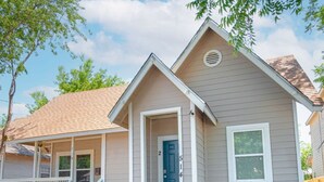 A single-story house with a front porch, a blue door, and a small window on the right side.