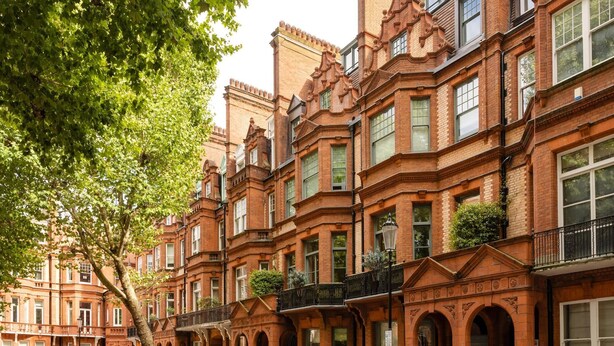 A row of red brick townhouses with arched windows and balconies, parked cars, and a tree in the foreground. - The King s Road Suite Next to Sloane Square (London)