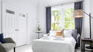 A hotel room with a large bed, a chair, a small table, and a lamp. - The King s Road Suite Next to Sloane Square (London)