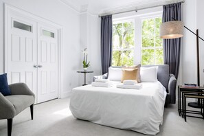 A hotel room with a large bed, a chair, a small table, and a lamp. - The King s Road Suite Next to Sloane Square (London)