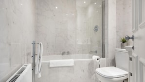 A modern bathroom with a glass-enclosed shower, a white toilet, and a built-in radiator.