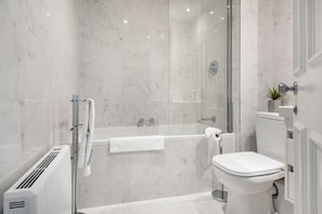 A modern bathroom with a glass-enclosed shower, a white toilet, and a built-in radiator.