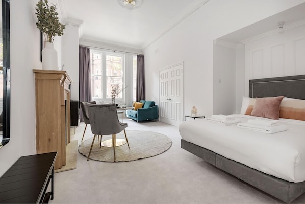 A modern bedroom with a large bed, a desk, a chair, and a sofa.