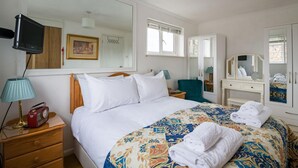 Ein Hotelzimmer mit einem Bett, Nachttisch, Lampe, Radio und einem großen Spiegel.