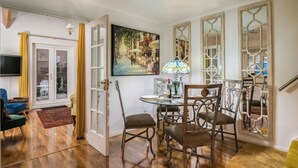 A dining area with a round table, chairs, and a painting on the wall.