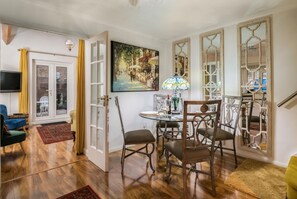 A dining area with a round table, chairs, and a painting on the wall.