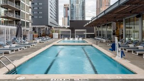 A rooftop pool with lounge chairs and a diving board, surrounded by high-rise buildings. - Austin Modern 1BD 1BA 2nd Street District Apartment (Austin)