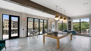 A spacious indoor area with a ping pong table, chairs, and large windows offering views of the outside. - Plano Beautiful Studio Apartment (Plano)