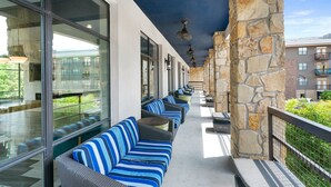 A covered outdoor seating area with striped cushions and stone walls. - Plano Beautiful Studio Apartment (Plano)