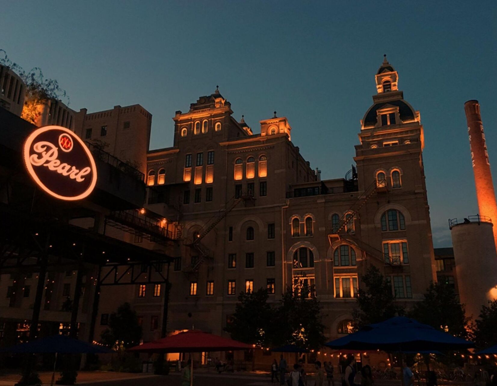 A historic building with arched windows and a clock tower, illuminated at dusk.