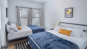 A bedroom with two beds, a ceiling fan, and a window with blinds. - Brand NEW Stylish 3BR 2BA Near Exciting Downtown (San Antonio)