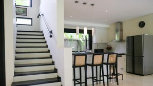 Eine moderne Küche mit Kochinsel, Barhocker und einem Edelstahl-Kühlschrank.