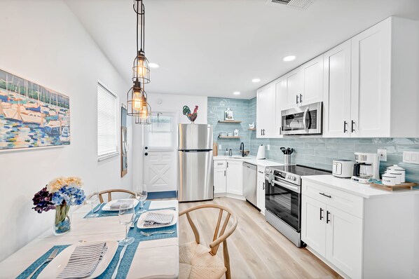 A modern kitchen with white cabinets, stainless steel appliances, and a blue tiled backsplash.