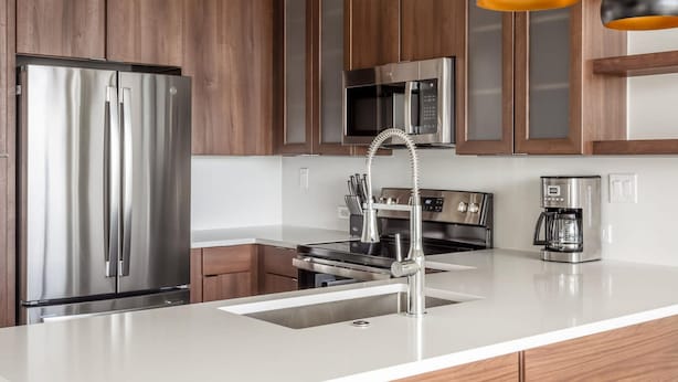 Une cuisine moderne dotée d’appareils électroménagers en acier inoxydable, de meubles en bois et de luminaires suspendus.