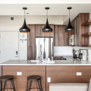 Une cuisine moderne dotée d’un îlot central, de meubles en bois et de luminaires suspendus.