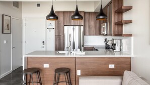 A modern kitchen with wooden cabinets, a central island, and pendant lighting. - Austin Dreamy 1BD 1BA 2nd Street District Apartment (Austin)