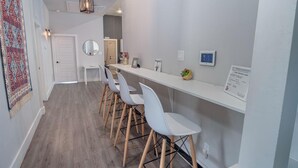 A modern kitchen with white bar stools, a long counter, and a hanging light fixture. - Gorgeous Family-friendly Home Near Downtown (San Antonio)