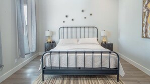 A bedroom with a bed, two bedside tables, a nightstand, a patterned rug, a ceiling fan, and a wall with decorative star-like objects. - Gorgeous Family-friendly Home Near Downtown (San Antonio)