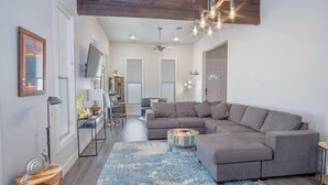 A modern living room with a sectional sofa, a wooden coffee table, and a blue patterned rug. - Gorgeous Family-friendly Home Near Downtown (San Antonio)