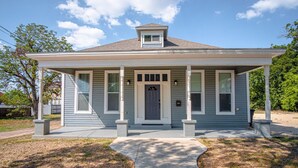 A single-story house with a covered porch, a front door, and a small garage. - Gorgeous Family-friendly Home Near Downtown (San Antonio)