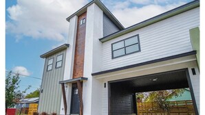 A modern two-story house with a garage, a visible chimney, and a front door. - Amazing 3BR 2BA Only 5 Mins From Downtown (San Antonio)