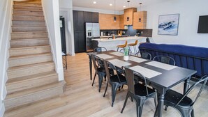 A modern kitchen with wooden cabinets, a central island, and a dining area with a table and chairs. - Amazing 3BR 2BA Only 5 Mins From Downtown (San Antonio)