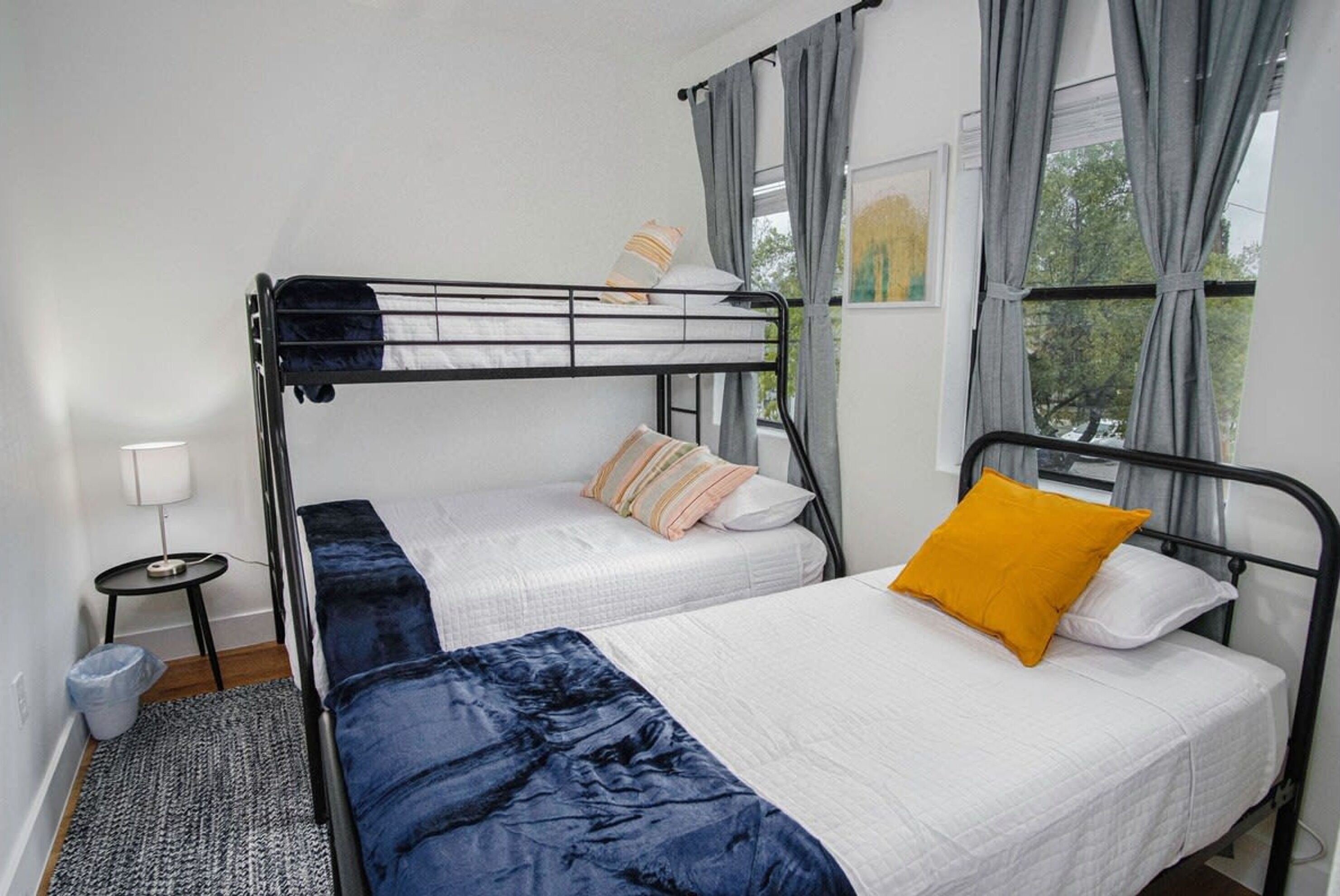 A room with two beds, a small table, and a window with curtains.