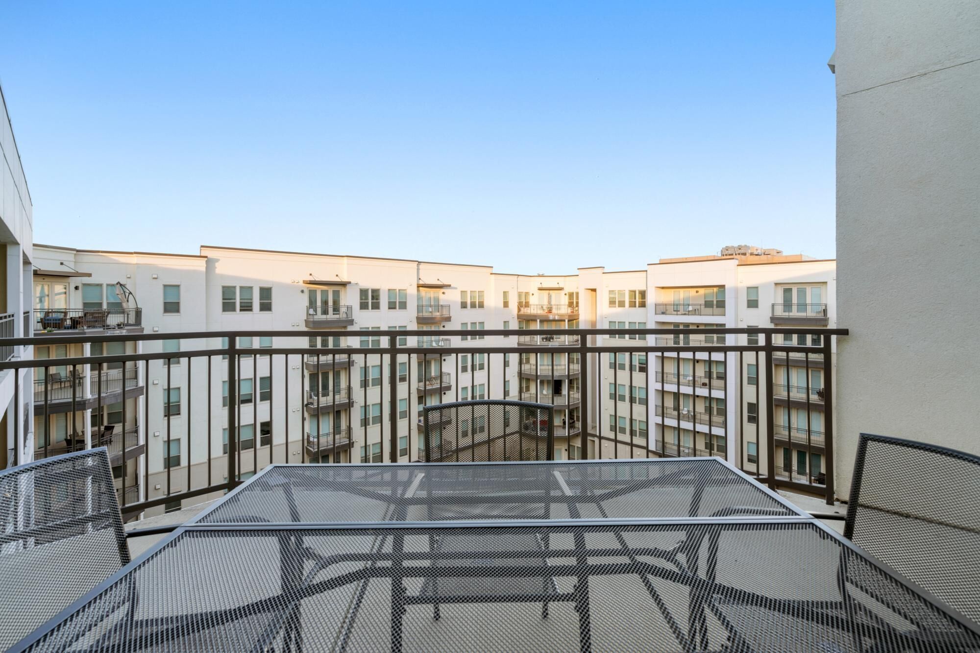 A modern apartment building with multiple balconies and a central courtyard.
