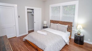 A bedroom with a bed, bedside tables, a closet, and a window with blinds.