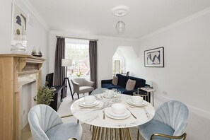 A dining area with a round table set for four, a sofa, and a fireplace.