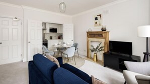 A modern living room with a fireplace, a dining area, and a kitchen visible through an open door. - The Knightsbridge Suite Next to Sloane Square (London)