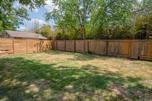 Backyard with a storage shed and a fenced area surrounded by trees.