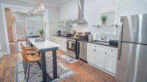 Une cuisine moderne avec des armoires blanches, des appareils en acier inoxydable et un îlot central doté de chaises.