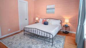 Une chambre à coucher avec un lit, deux tables de chevet avec des lampes, un tableau au mur et une porte.