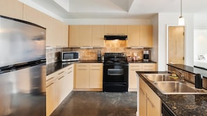 A modern kitchen with stainless steel appliances, wooden cabinets, and a granite countertop. - Austin Exclusive 1BD 1BA 2nd Street District Apartment (Austin)