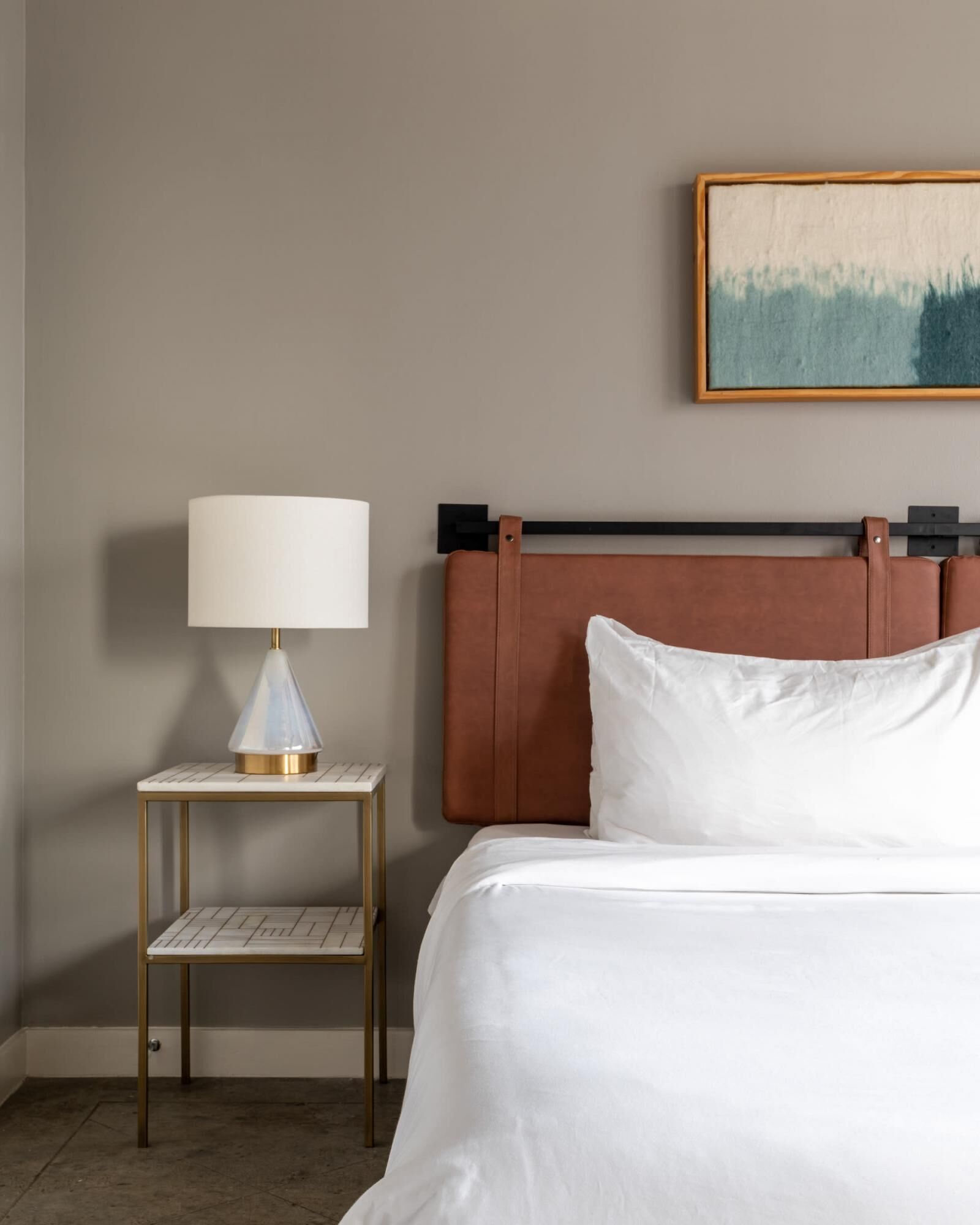 Ein Hotelzimmer mit einem Bett, einem Nachttisch mit einer Lampe und einem Gemälde an der Wand.