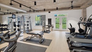 Une salle de sport moderne équipée de divers appareils d’exercice, notamment des tapis de course, des appareils de musculation et des poids libres.