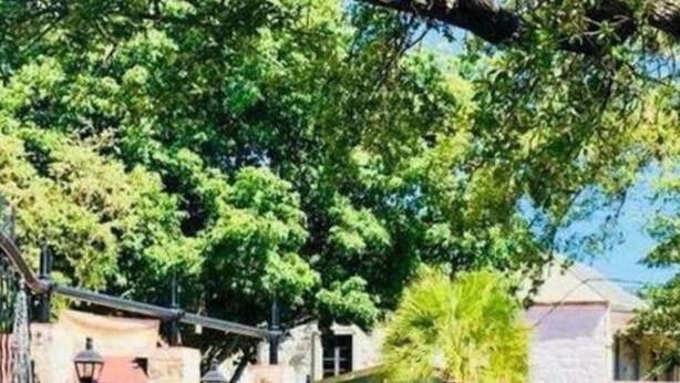 A train station platform with a blue structure, greenery, and a building in the background. - Fascinating 2BR 1BA Near Festive DT and Riverwalk (San Antonio)