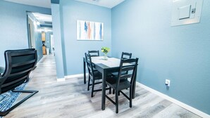 A dining area with a table set for four, surrounded by chairs, in a room with light blue walls and wooden flooring. - Fascinating 2BR 1BA Near Festive DT and Riverwalk (San Antonio)