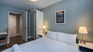 A hotel room with a bed, two bedside tables, a chair, a wardrobe, and a framed picture on the wall. - Fabulous Fulham (London)